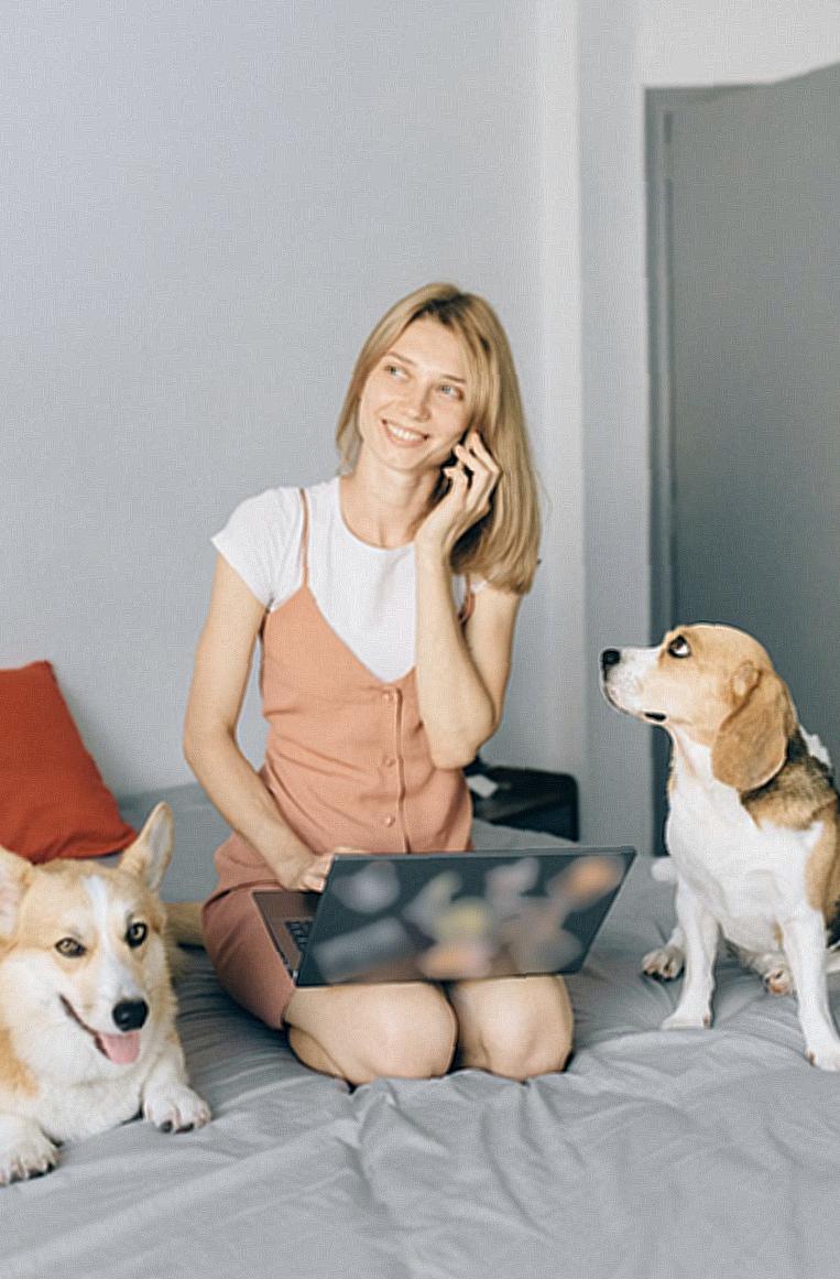 A Woman Talking on the Phone with Her Dogs in the Bed