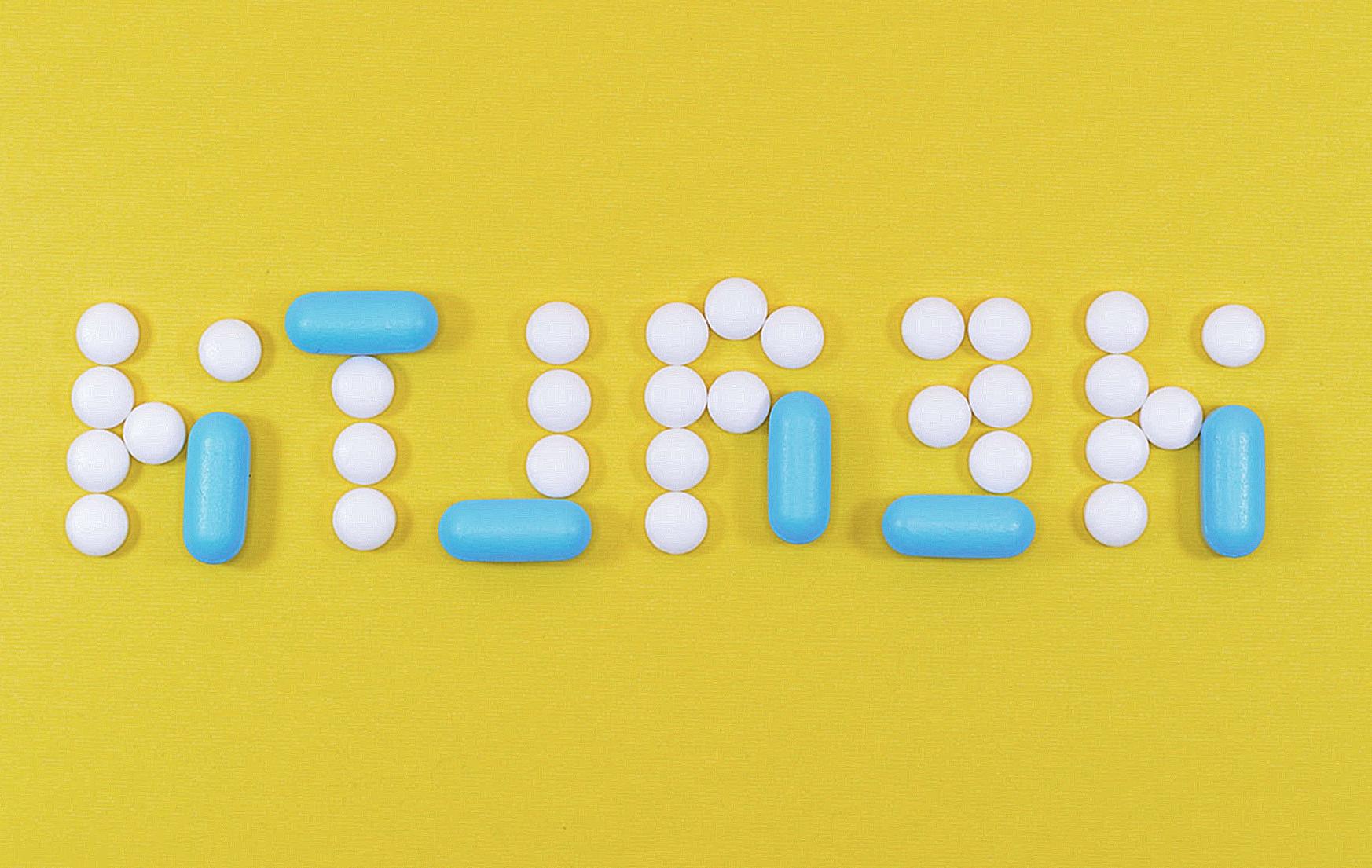 White and Blue Health Pill and Tablet Letter Cutout on Yellow Surface