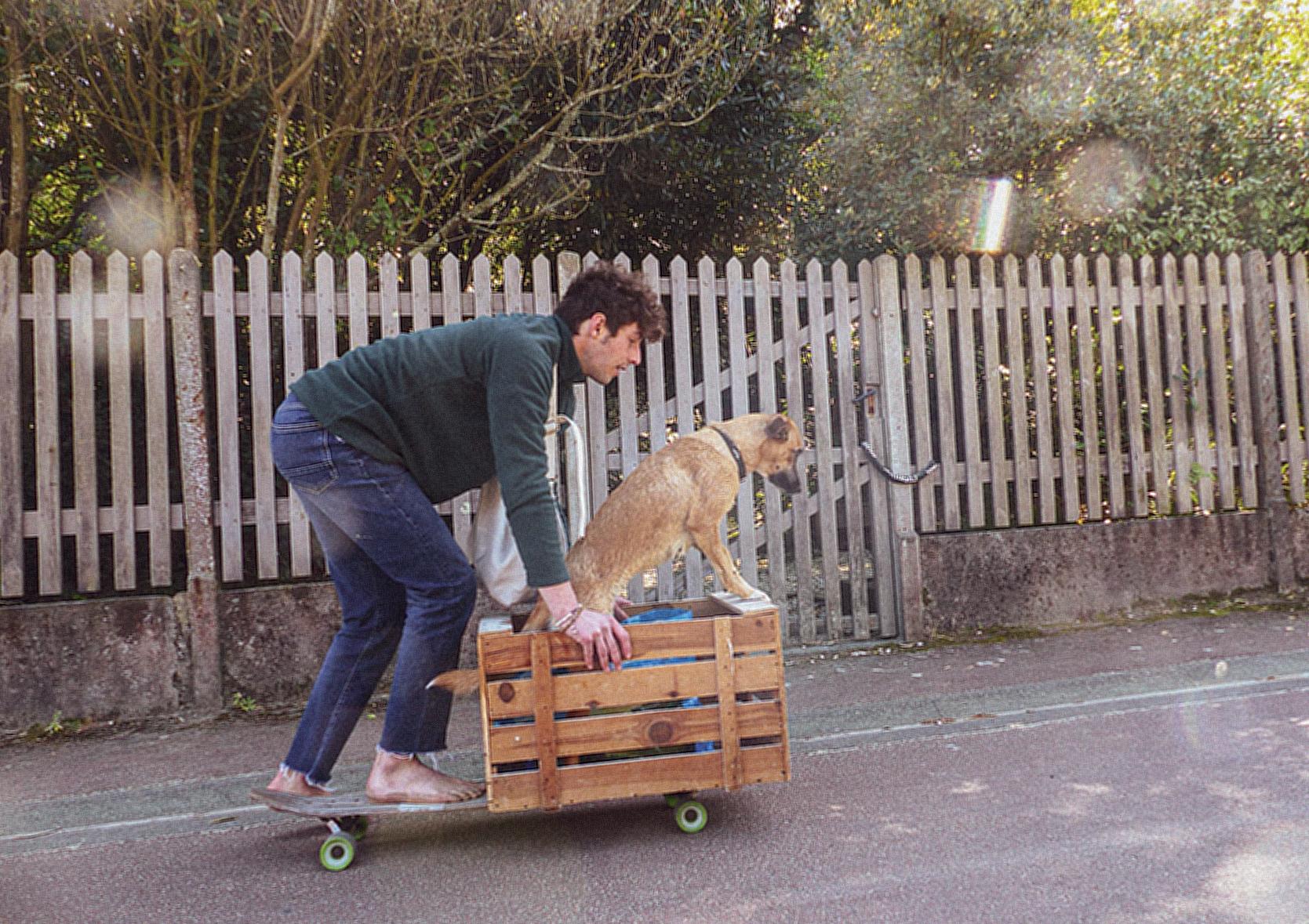 A Man Riding a Skateboard with His Dog on a Wooden Crate 