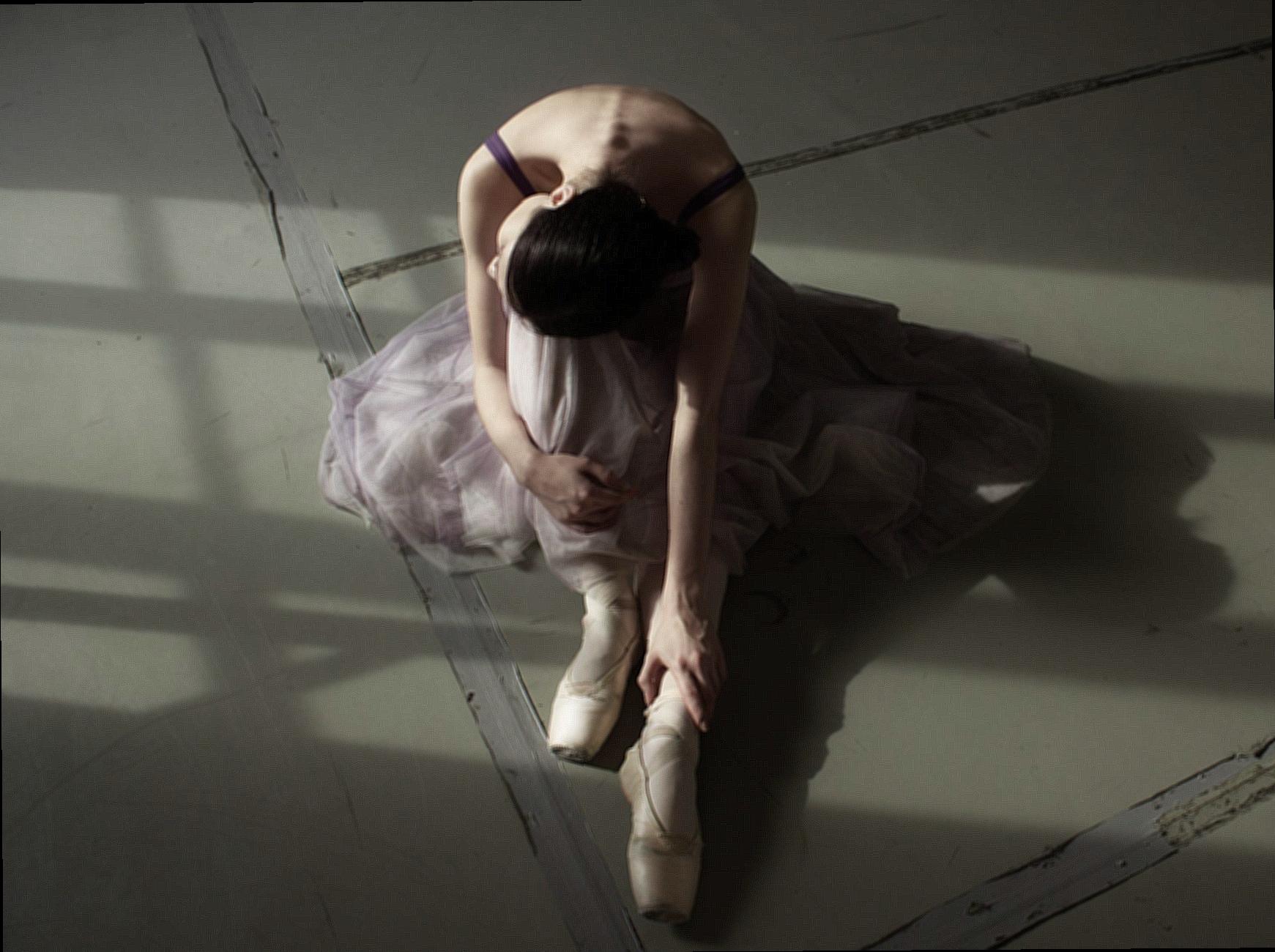 Unrecognizable graceful ballet dancer resting on floor